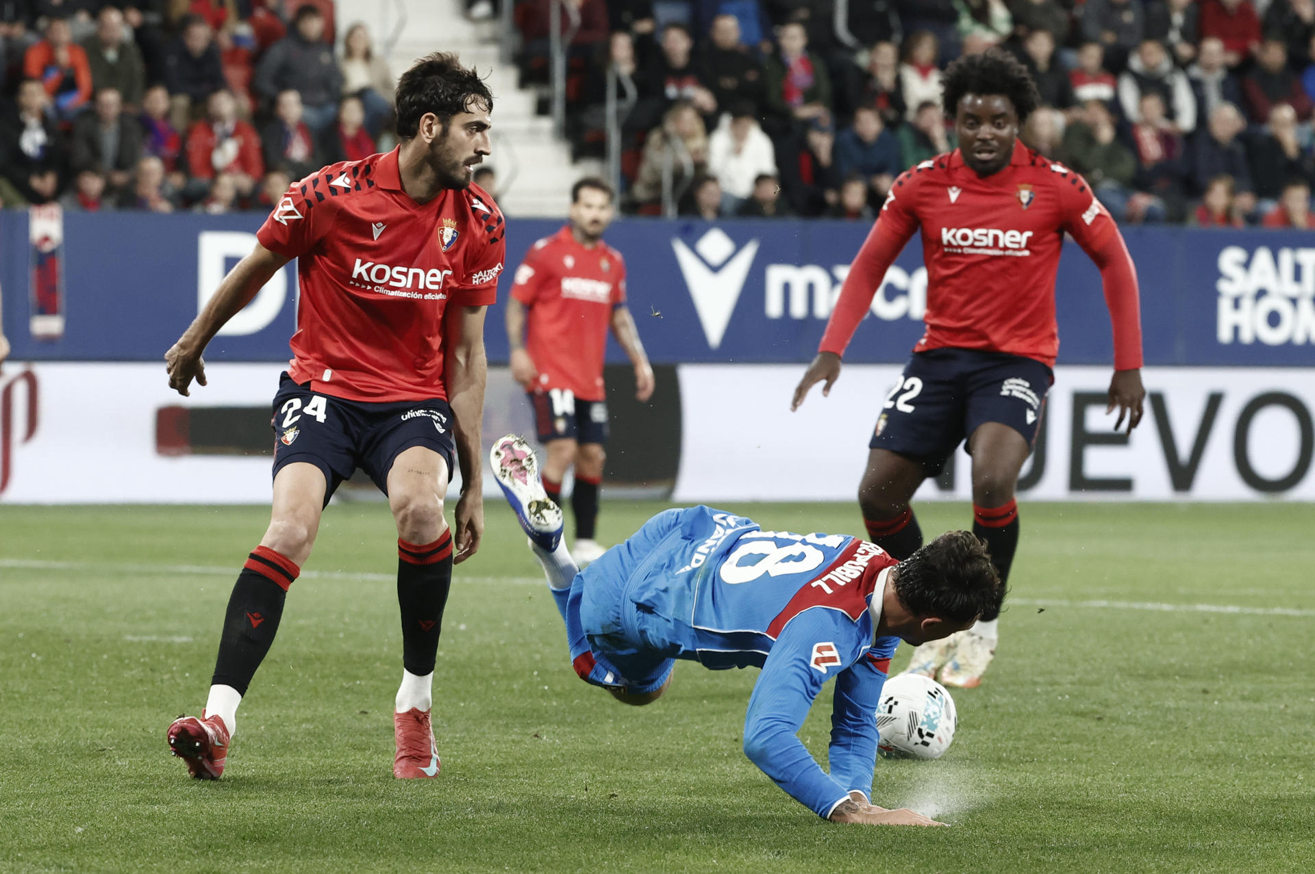 El defensa del Atlético de Madrid Marc Pubill (c) cae junto a Alejandro Catena (i), de Osasuna, durante el partido de la jornada 36 de LaLiga que disputan CA Osasuna y Atlético de Madrid, este martes en el estadio de El Sadar, en Pamplona. EFE/ Jesús Diges
