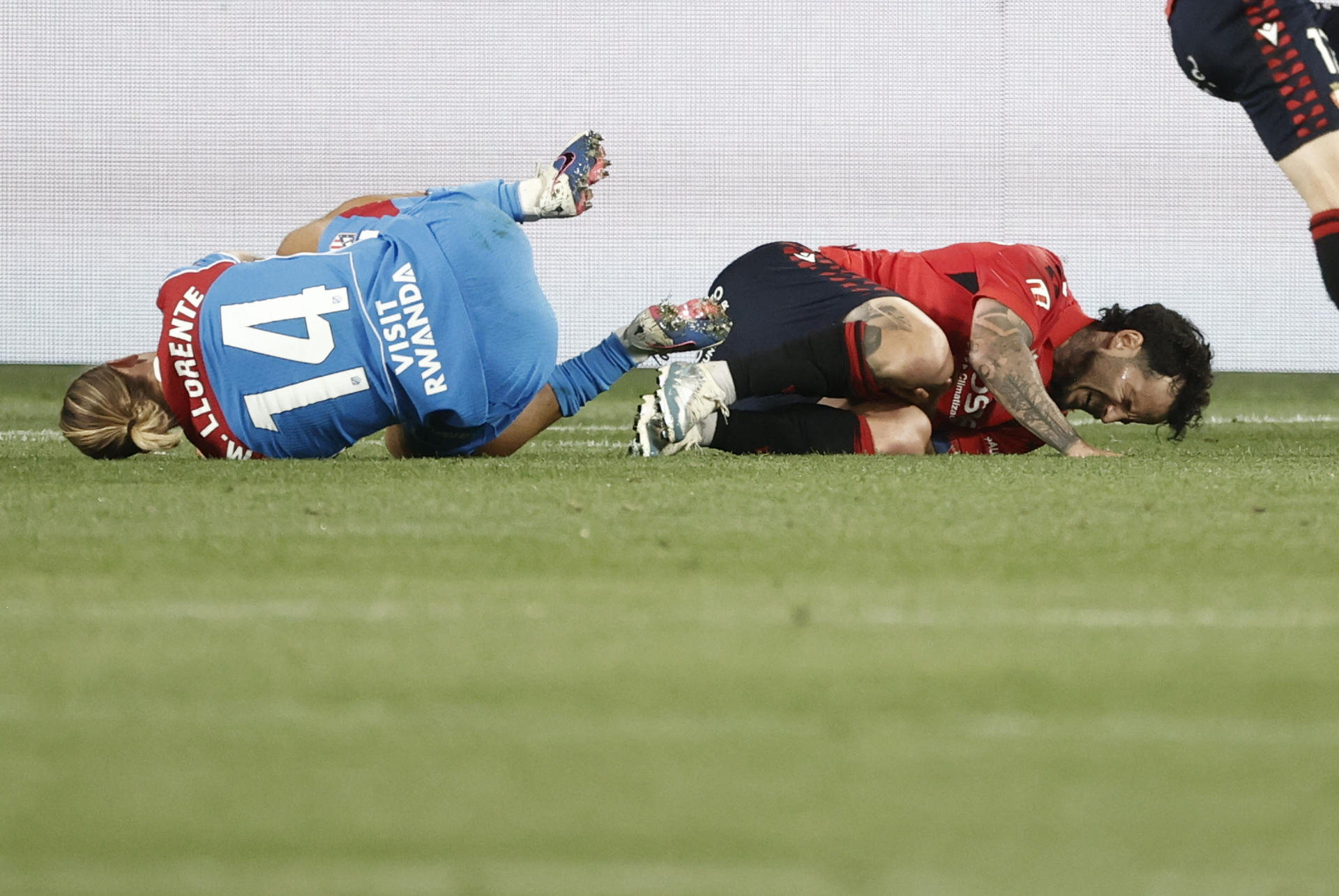 El centrocampista de Osasuna Rubén García (d) y Marcos Llorente, del Atlético de Madrid, se duelen en el suelo durante el partido de la jornada 36 de LaLiga que disputan CA Osasuna y Atlético de Madrid, este martes en el estadio de El Sadar, en Pamplona. EFE/ Jesús Diges
