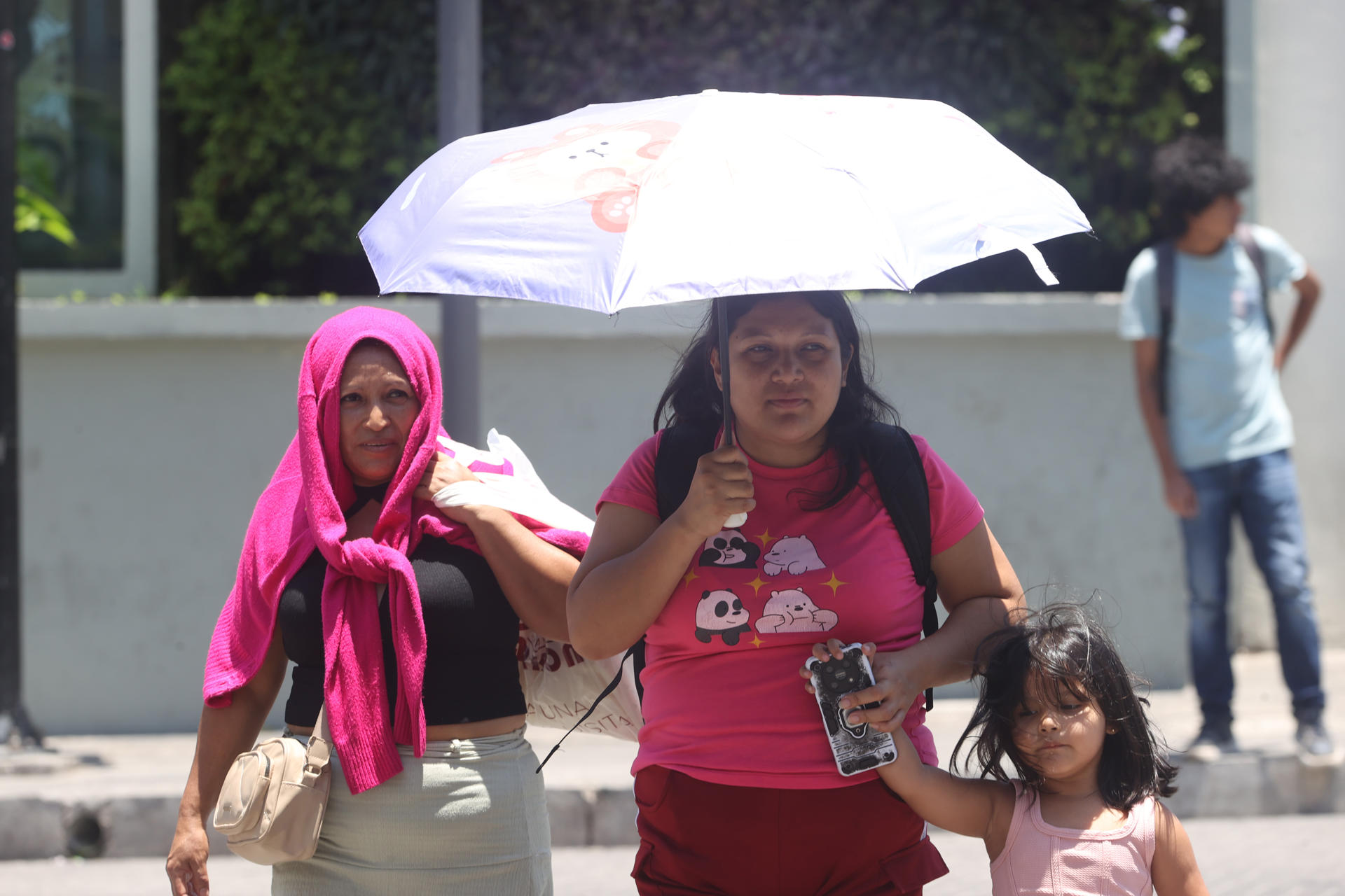 Tres mujeres fueron captadas este 12 de mayo al protegerse del sol, en medio de una ola de calor que genera "temperaturas extremas" superiores a los 40 grados Celsius, en San Salvador (El Salvador). EFE/Javier Aparicio
