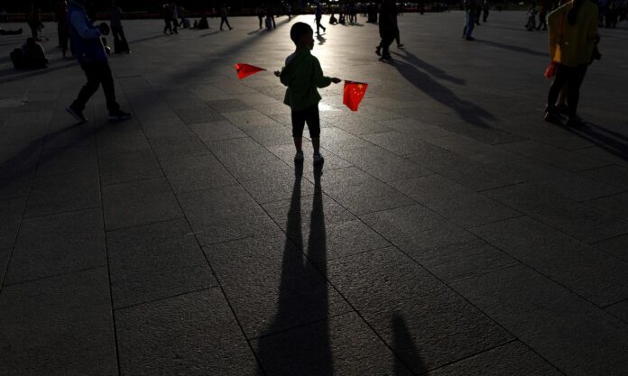 Imagen de archivo de un niño con dos banderas chinas en la plaza de Tiananmen en Pekín. EFE/ How Hwee Young[ATTENTION: This Image is part of a PHOTO SET]
