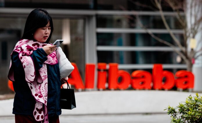 Imagen de archivo de una mujer pasando por delante del logo de Alibaba en su edificio en el Parque Xuhui Binjiang de Shanghái, China. EFE/EPA/ALEX PLAVEVSK
