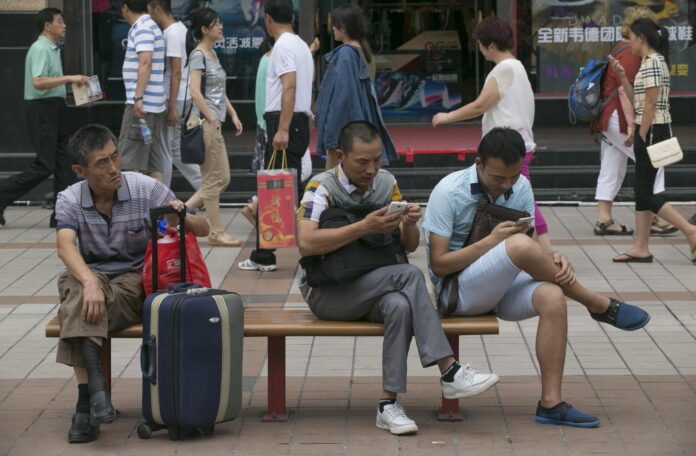En la imagen de archivo, dos ciudadanos utilizan sus teléfonos móviles en un banco en un distrito comercial en Pekín (China). EFE/Rolex Dela Pena
