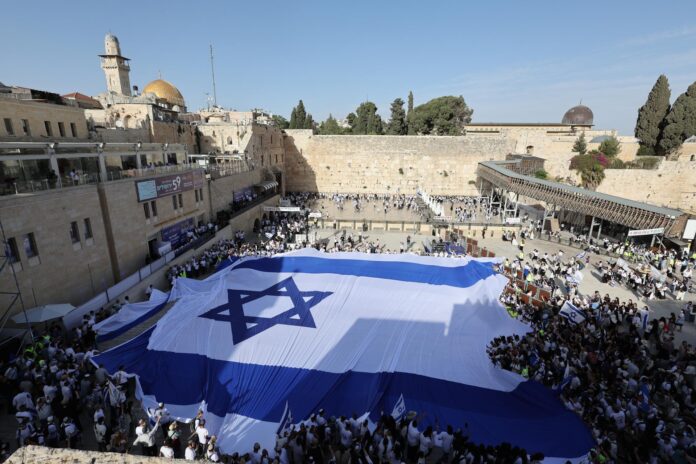 - Jóvenes israelíes despliegan una gran bandera israelí en la plaza del Muro de los Lamentos durante las 59ª celebraciones del Día de Jerusalén y la 'Marcha de las Banderas' en la Ciudad Vieja de Jerusalén, 14 de mayo de 2026. La marcha anual conmemora el establecimiento del control israelí sobre la Ciudad Vieja y sus lugares sagrados tras la Guerra de los Seis Días de 1967. (Jerusalén) EFE/EPA/ABIR SULTAN

