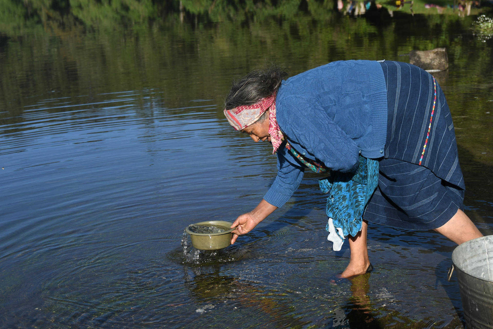 Una indígena de la etnia maya fue captada este 14 de mayo al recoger agua durante una ceremonia ancestral en la laguna de Chicabal, en San Martín Sacatepéquez (Guatemala). EFE/Alex Cruz