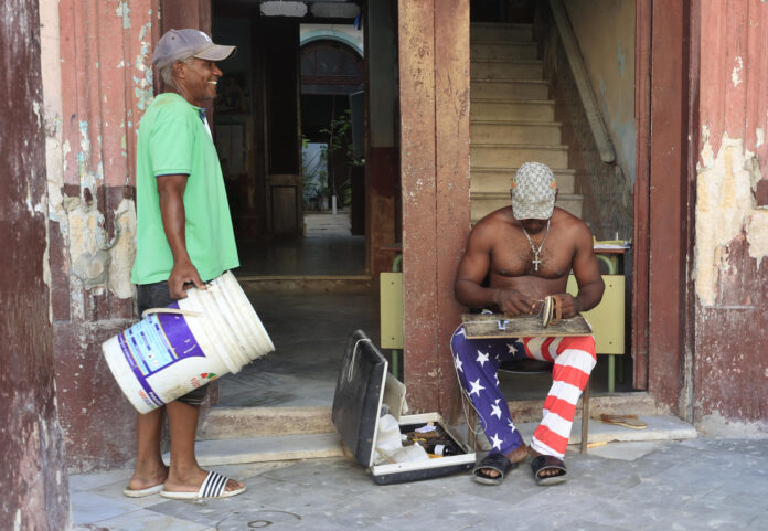 Fotografía de un zapatero arreglando calzado y hablando con otra persona en una calle de La Habana (Cuba) del 8 de mayo de 2026. EFE/Ernesto Mastrascusa
