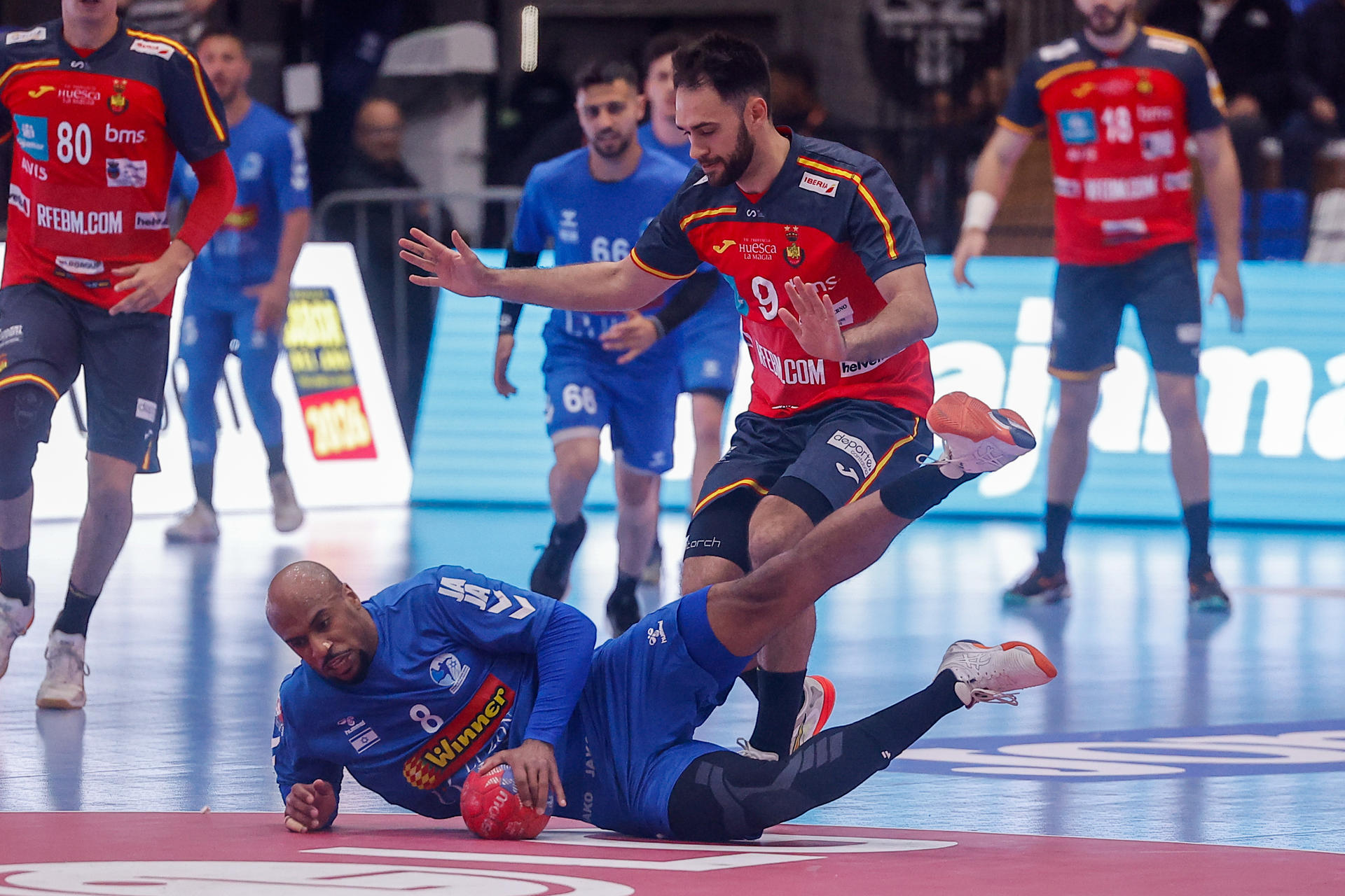 Ian Tarrafeta (c), de España, disputa un balón con Daniel Mosindi (abajo), de Israel, en un partido clasificatorio para el Mundial 2027 en el estadio La Casa del Handball Argentino, en Buenos Aires (Argentina). EFE/Juan Ignacio Roncoroni
