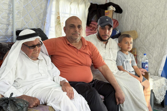 Yahya Abdelwahid Al Taybi (i), de 90 años, posa en la tienda de campaña en la que se encuentra refugiado junto a su familia en el barrio de Sheij Radwan de la ciudad de Gaza. EFE/ Ahmad Awad
