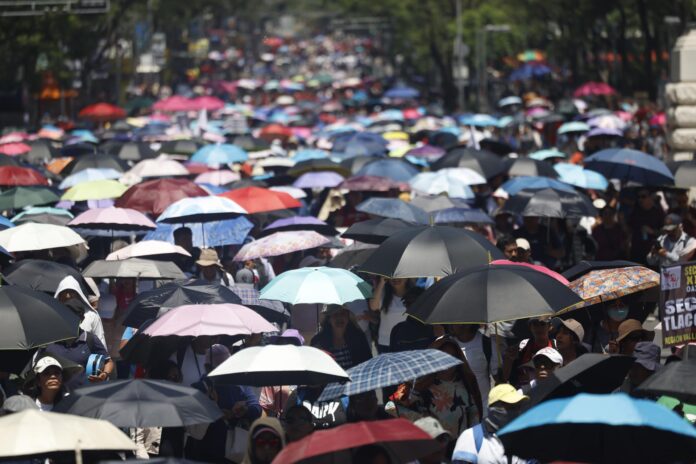 Maestros de la Coordinadora Nacional de Trabajadores de la Educación (CNTE) sostienen sombrillas durante una protesta este viernes, en Ciudad de México (México). EFE/ Sáshenka Gutiérrez
