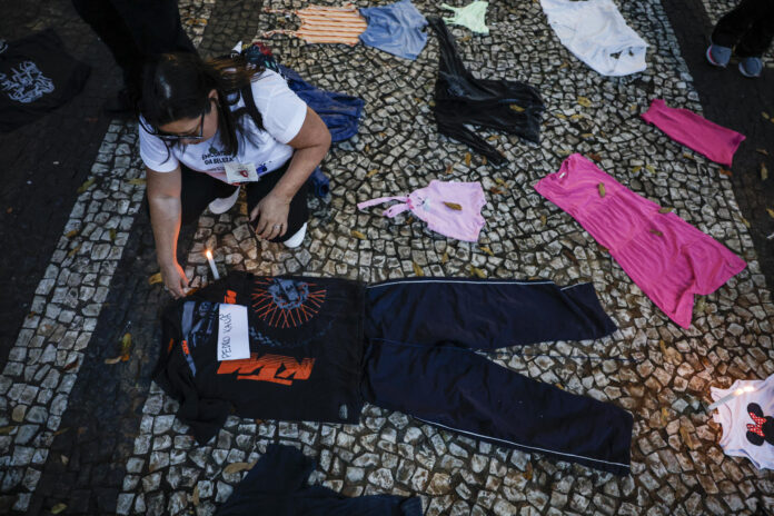 Una integrante del movimiento Madres de Mayo coloca una vela junto a algunas prendas durante una manifestación este sábado, en Sao Paulo (Brasil). EFE/ Sebastiao Moreira
