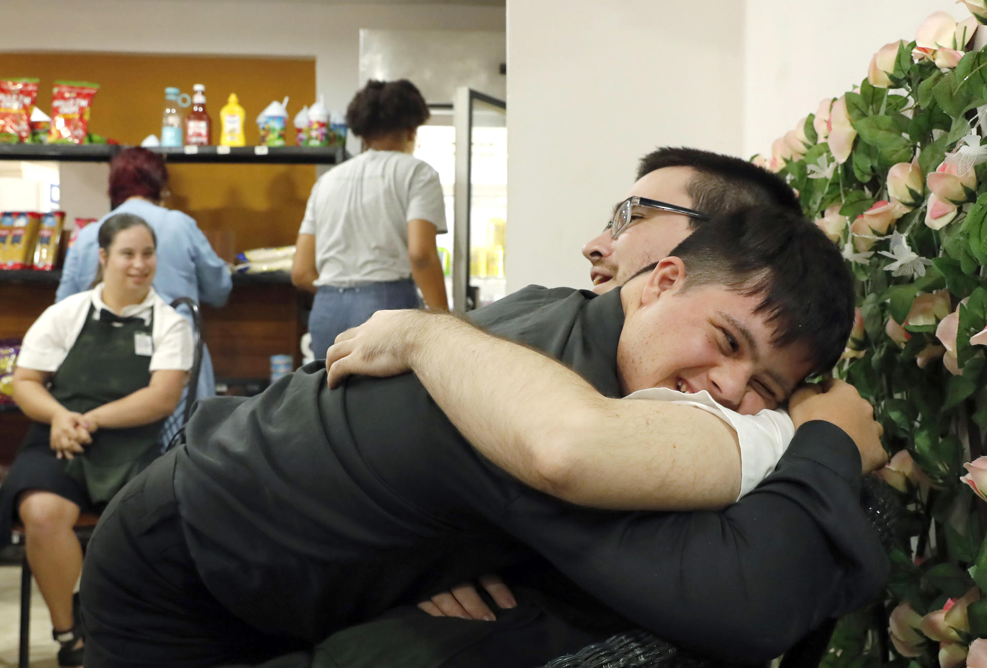 El joven Livan Valle (i), abraza a uno de sus compañeros de trabajo en una cafetería en La Habana (Cuba). EFE/ Ernesto Mastrascusa
