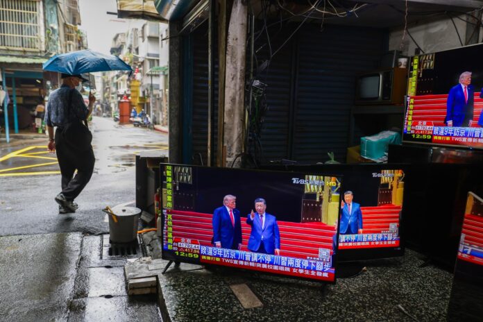 TAIPEI (Taiwán), 14/05/2026.- Un peatón pasa junto a una tienda de segunda mano y reparación de televisores, con pantallas que transmiten la reunión en Pekín entre el presidente estadounidense, Donald Trump, y el chino, Xi Jinping, en Taipéi, Taiwán, el 14 de mayo de 2026. 
EFE/EPA/RITCHIE B. TONGO
