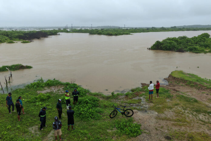 Fotografía de archivo que muestra a personas observando las inundaciones en la localidad de Chanduy en Santa Elena (Ecuador). EFE/ Gerardo Menoscal
