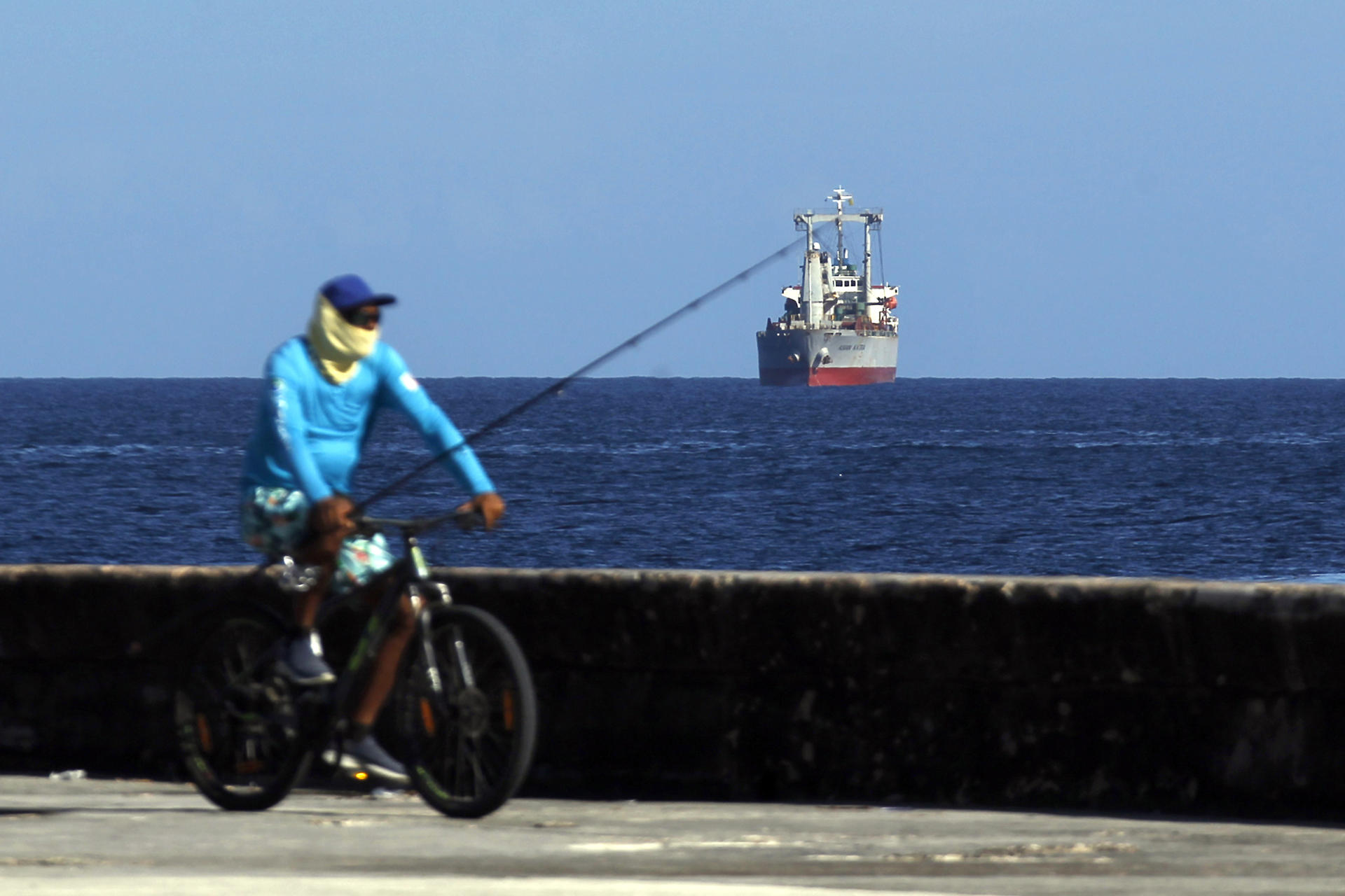 AME2576. LA HABANA (CUBA), 18/05/2026.- Una persona monta en bicicleta frente a la llegada de un barco con ayuda humanitaria este lunes, a La Habana (Cuba). El barco mercante Asian Katra atracó en la bahía de La Habana con ayuda humanitaria procedente de México y Uruguay para el pueblo cubano, que sufre apagones y una profunda crisis económica gravada por el bloqueo petrolero de EEUU. EFE/ STR
