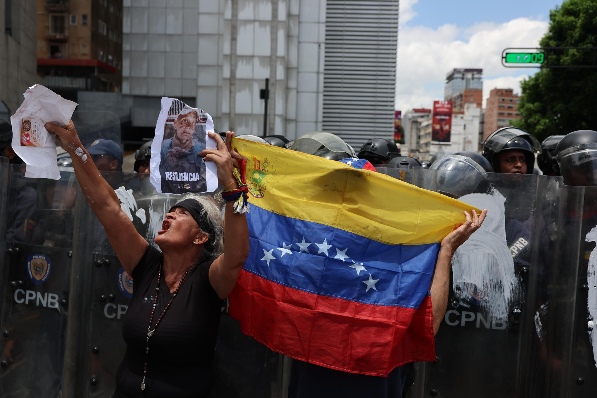 Una persona muestra carteles frente a integrantes del Cuerpo de Policía Nacional Bolivariana (CPNB) este lunes, durante un homenaje por la muerte de Carmen Navas, en Caracas (Venezuela). EFE/ Miguel Gutiérrez
