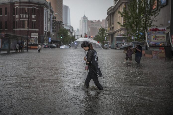 Una mujer camina por una calle inundada mientras se protege de la lluvia con un paraguas en Shenyang, China, en una imagen de archivo. EFE/ROMAN PILIPEY
