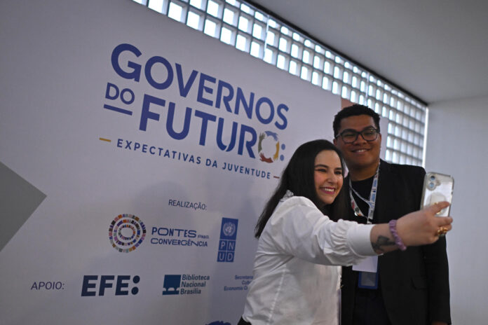 Personas posan para una foto durante el foro 'Gobiernos del Futuro: Expectativas de la Juventud' este martes, en la Biblioteca Nacional de Brasilia (Brasil). La juventud de América Latina mantiene su respaldo a la democracia, aunque la condiciona a la capacidad del Estado para ofrecer resultados concretos frente a la desigualdad y la inclusión, según una nueva encuesta elaborada por el Programa de las Naciones Unidas para el Desarrollo (PNUD). EFE/ Andre Borges
