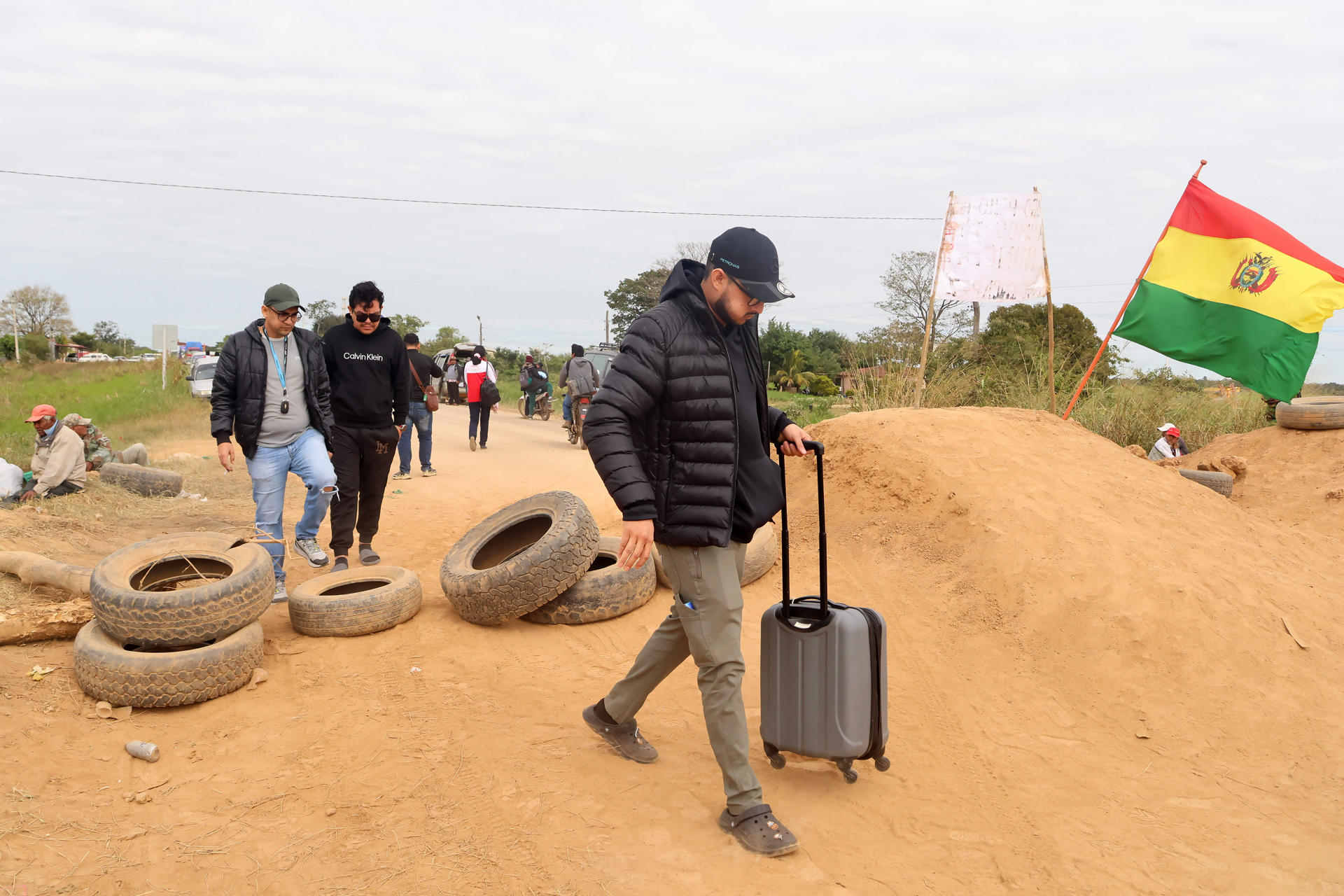 Personas cruzan por un bloqueo en una vía en San Julián (Bolivia). EFE/ Juan Carlos Torrejon
