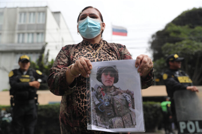 Una mujer sostiene una fotografía durante un plantón frente a la embajada de Rusia este martes, en Lima (Perú). EFE/ Paolo Aguilar
