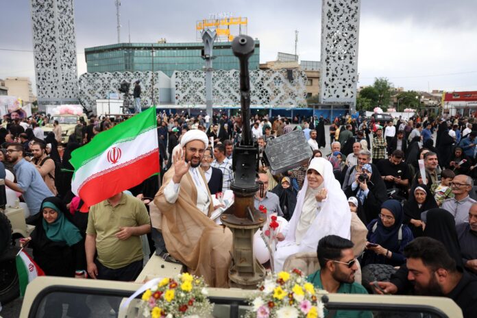 Una pareja iraní llega en un vehículo militar durante una ceremonia nupcial colectiva organizada en el marco de la campaña 
