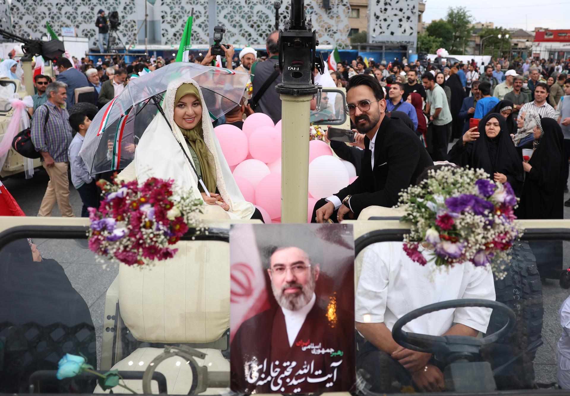 Una pareja iraní llega en un vehículo militar a una ceremonia nupcial colectiva organizada en el marco de la campaña "Jan-Fada" (Sacrificio de la Vida) en Teherán, Irán, el 18 de mayo de 2026. El conflicto entre Irán y Estados Unidos continúa, mientras el presidente estadounidense Donald Trump reitera sus amenazas de nuevas acciones militares contra Irán.
 (Teherán) EFE/EPA/ABEDIN TAHERKENAREH
