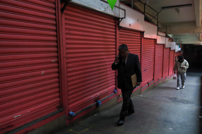 Personas caminan cerca de tiendas y puestos de comida cerrados este miércoles, en La Paz (Bolivia). EFE/ Gabriel Márquez
