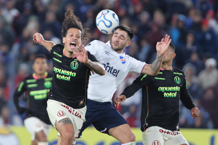 Maximiliano Gomez (c), de Nacional, disputa un balón con Williams Riveros (i) y Anderson Santamaría, de Universitario, en un partido de la fase de grupos de la Copa Libertadores entre el Club Nacional y Universitario de Deportes en el estadio Gran Parque Central en Montevideo (Uruguay). EFE/ Gastón Britos
