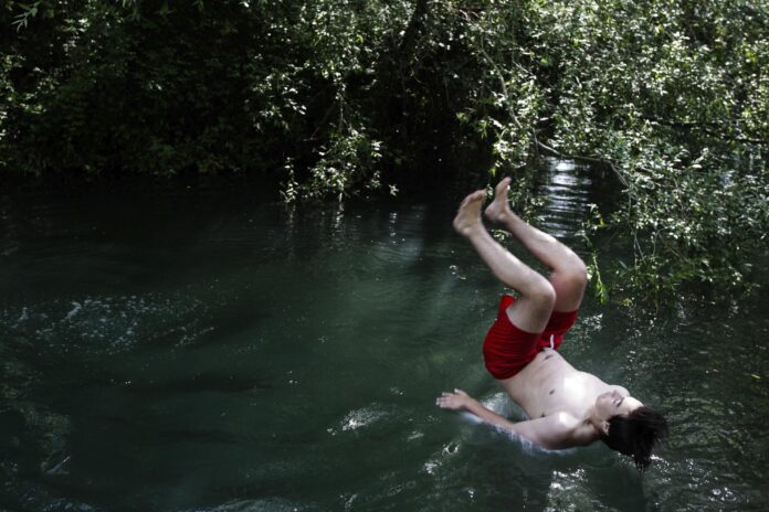 Un joven se zambulle en el río Lis a su paso por Leiria (Portugal), en una imagen de archivo. EFE/Paulo Cunha
