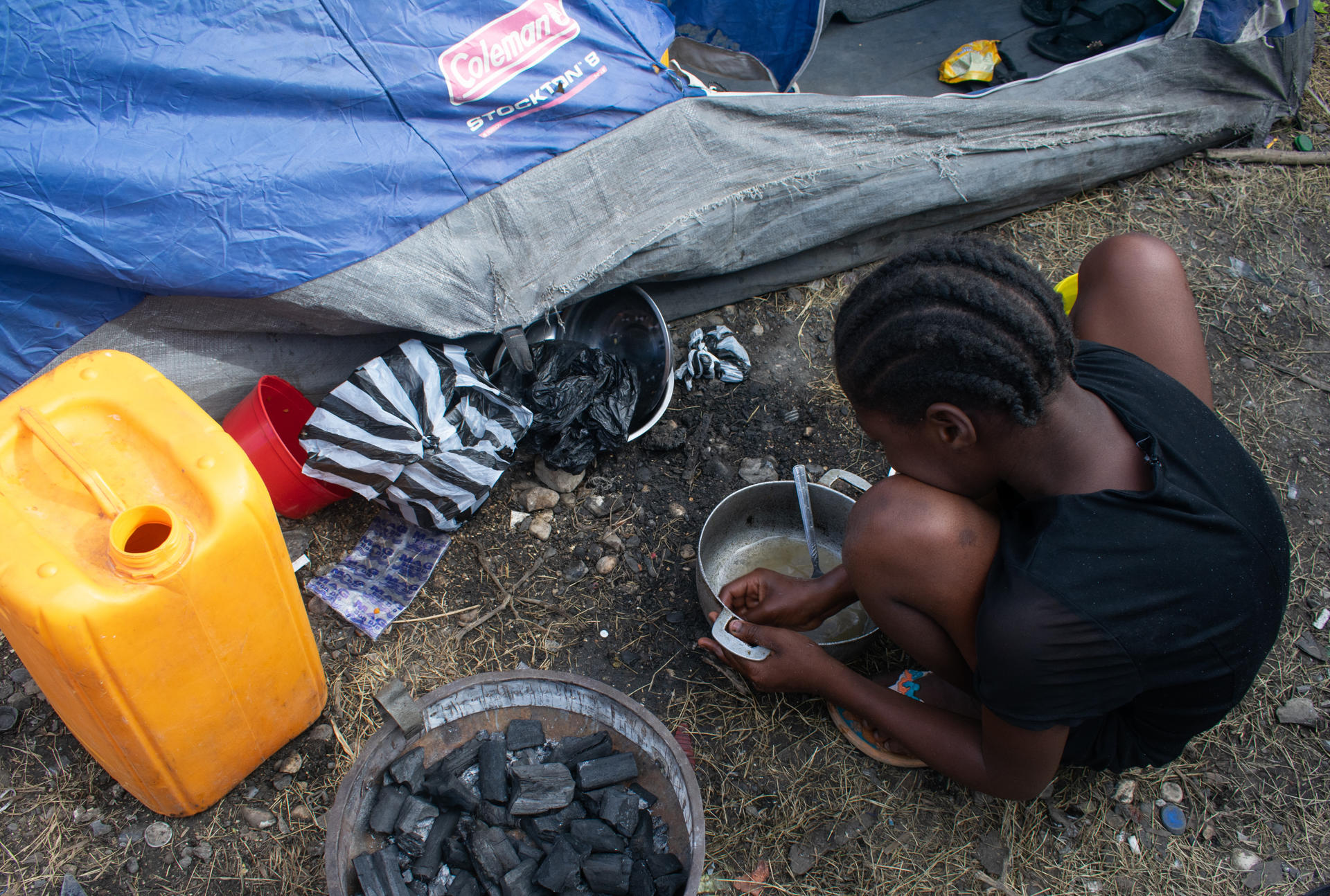 Una niña desplazada por la violencia, limpia una olla en un campamento de refugiados este jueves, en Puerto Príncipe (Haití). . EFE/ Jonet St Élois