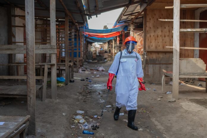 Un trabajador sanitario, con equipo de protección, fue captado este 23 de mayo al desinfectar los puestos de un mercado en Bunia (provincia de Ituri, República Democrática del Congo), para frenar la propagación del virus del ébola. EFE/STRINGER
