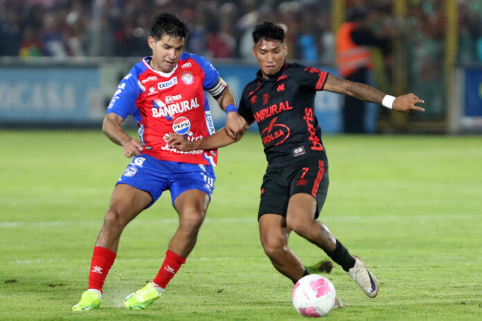 Jesús López, de Xelajú MC (i), disputa un balón con Rudy Muñoz, de Municipal, este sábado en la final de la Liga Nacional de Fútbol de Guatemala, en el estadio Mario Camposeco, en Quetzaltenango. EFE/ Fernando Ruiz
