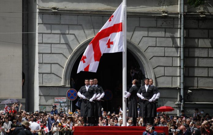 Hombres georgianos vestidos con trajes nacionales izan la bandera nacional georgiana durante un desfile militar con motivo del Día de la Independencia del país en Tiflis, Georgia, el 26 de mayo de 2026. EFE/EPA/DAVID MDZINARISHVILI
