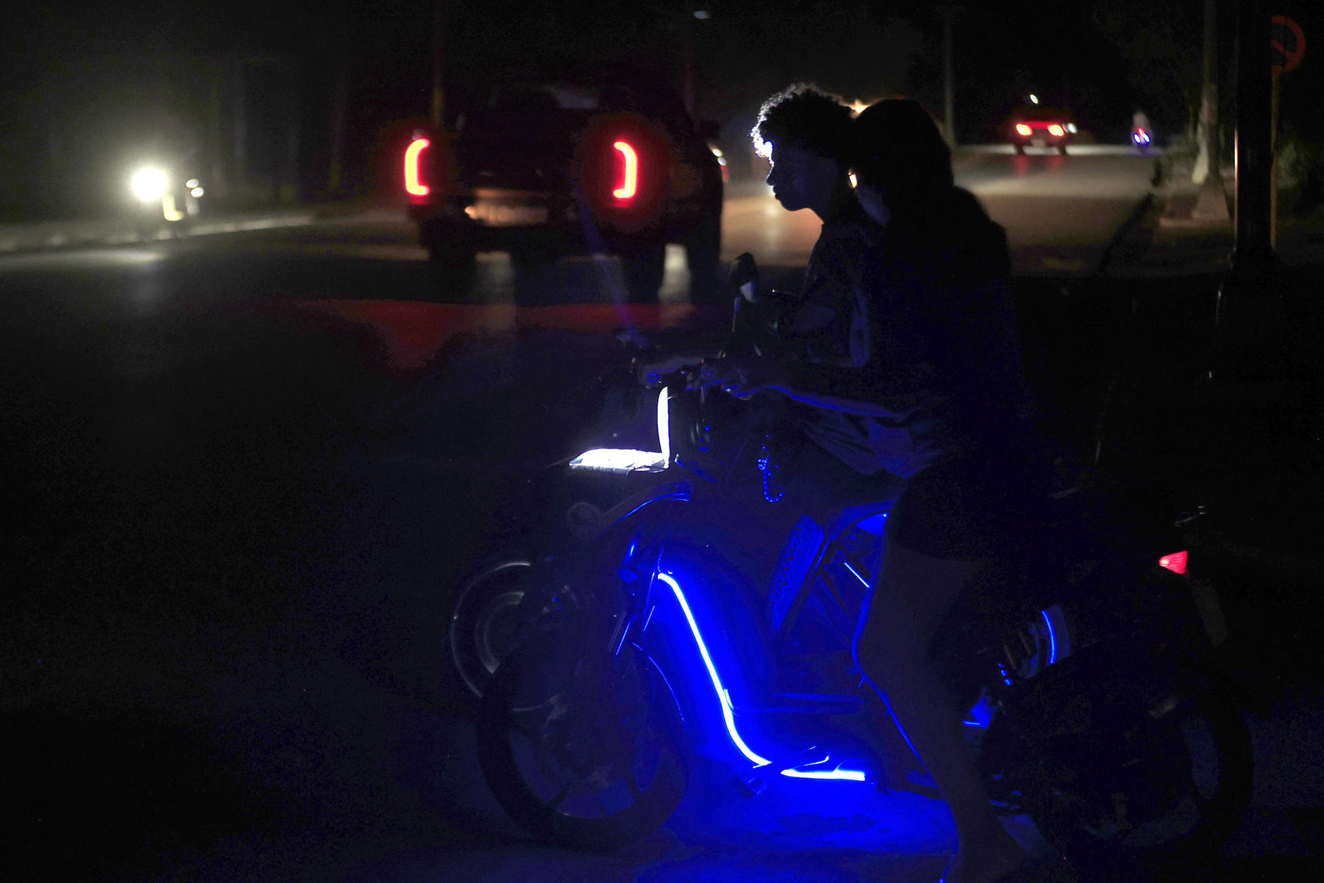 Personas en motos eléctricas esperan durante un apagón este lunes, en La Habana (Cuba). EFE/ Ernesto Mastrascusa