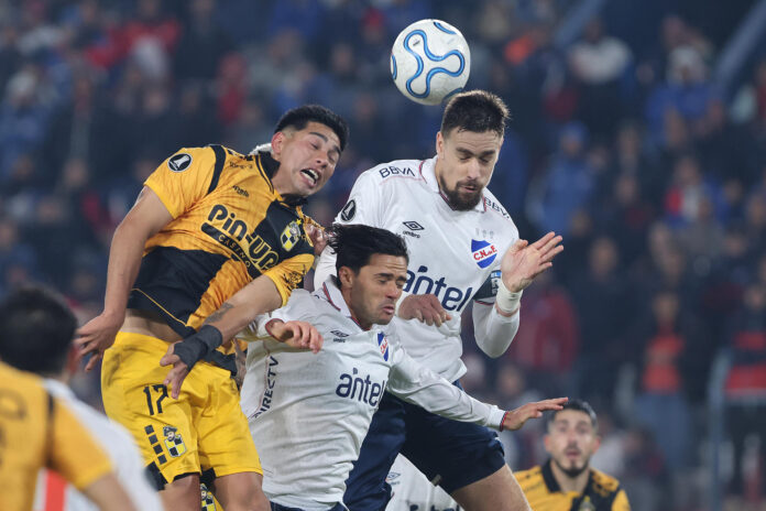 Sebastián Coates (d) y Nicolás Rodríguez (c), de Nacional, disputan un balón con Francisco Salinas, de Coquimbo, durante un partido de la fase de grupos de la Copa Libertadores entre el Club Nacional y Coquimbo Unido en el estadio Gran Parque Central en Montevideo (Uruguay). EFE/Gastón Britos
