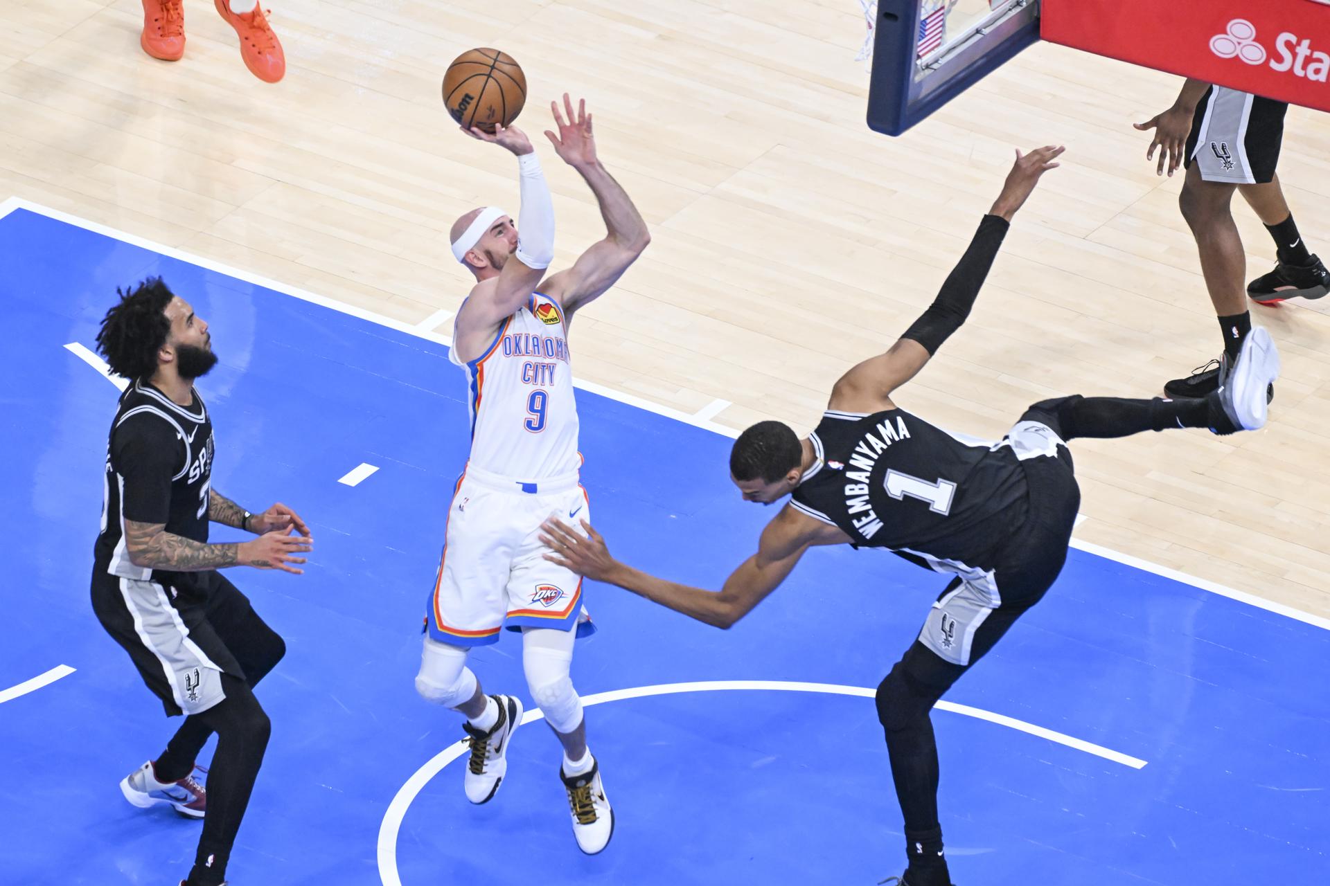 El base de Oklahoma City Thunder, Alex Caruso (i), lanza a canasta tras la marca descontrolada del alero/pívot de San Antonio Spurs Victor Wembanyama (d) durante el quinto partido de las Finales de la Conferencia Oeste de la NBA jugado este martes en Oklahoma City. EFE/EPA/MANUELA SOLDI SHUTTERSTOCK OUT
