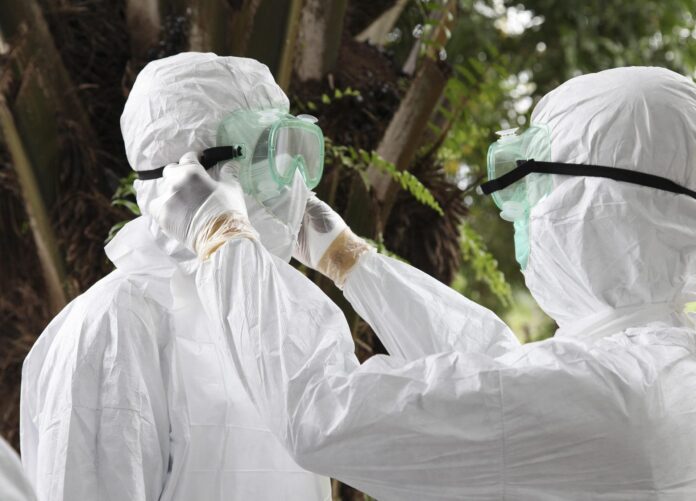 En la imagen de archivo, dos enfermeros liberianos mientras revisan sus equipos de protección individual antes de transportar el cuerpo de una víctima del ébola para su entierro. EFE/Ahmed Jallanzo
