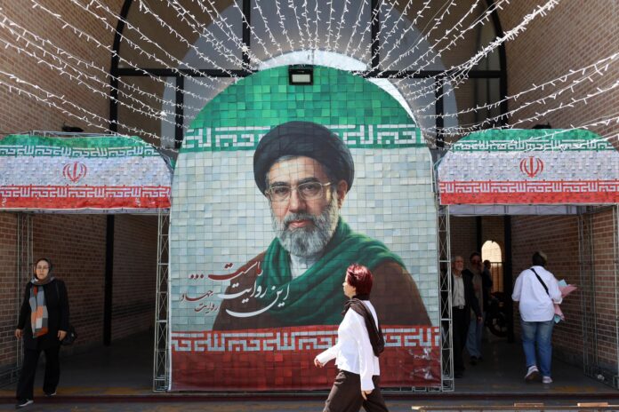 Fotografía del 6 de mayo de 2026 de iraníes caminando junto a una imagen del líder supremo de Irán, el ayatolá Mojtaba Jameneí, en una calle de Teherán, Irán. EFE/EPA/ABEDIN TAHERKENAREH
