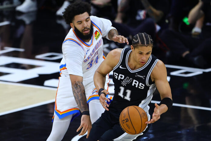 Carter Bryant (d), de Spurs, disputa un balón con Kenrich Williams, de Thunder, en el AT&T Center en San Antonio (EE.UU.). EFE/Carlos Ramírez
