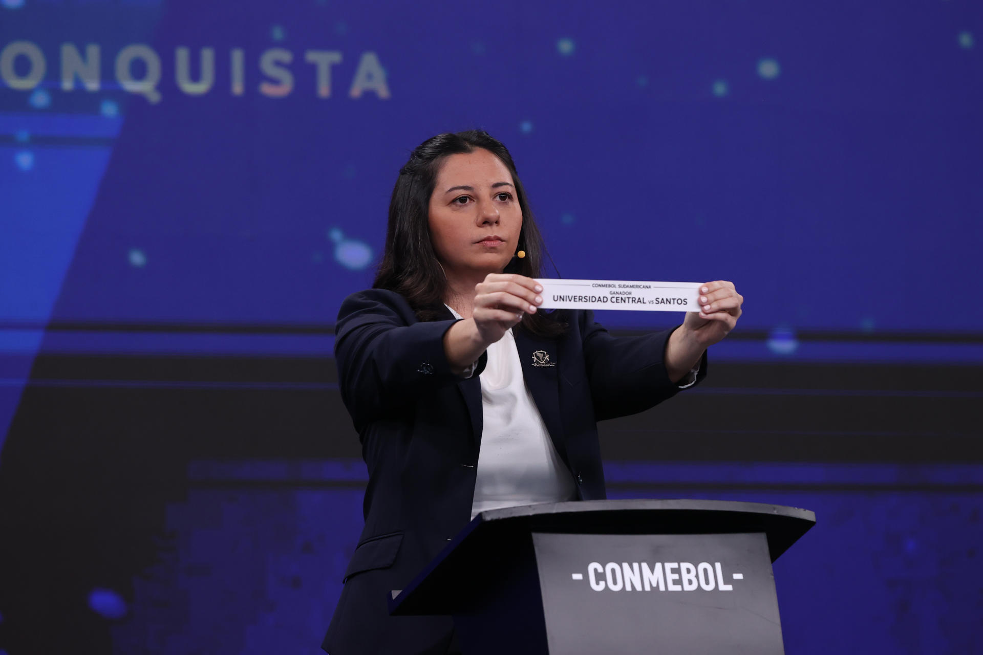 La representante de Conmebol Luciana Antunes sostiene la papeleta que anuncia el enfrentamiento entre Universidad Central y Santos durante el sorteo de octavos de final de la Copa Sudamericana en Asunción (Paraguay). EFE/ Juan Pablo Pino