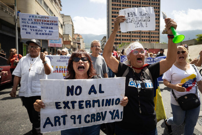Personas sostienen carteles durante una protesta liderada por adultos mayores en Caracas (Venezuela). EFE/ Ronald Peña R
