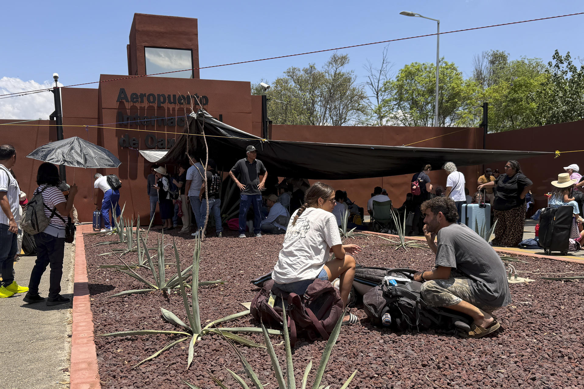 Personas esperan afuera del Aeropuerto Internacional de Oaxaca este viernes, en Oaxaca (México). EFE/ Jesús Méndez