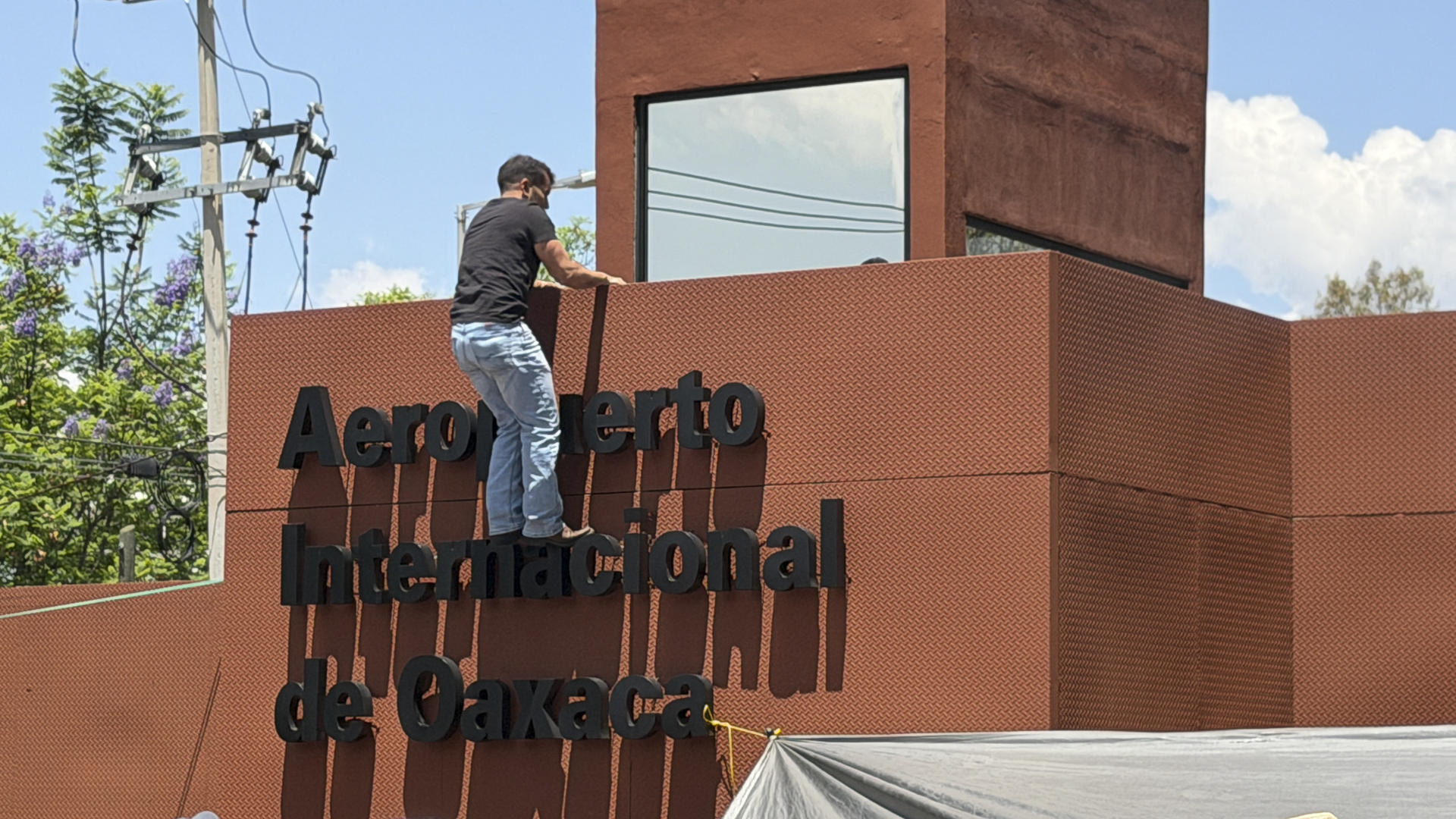 Una persona sube una pared del Aeropuerto Internacional de Oaxaca este viernes, en Oaxaca (México). EFE/ Jesús Méndez
