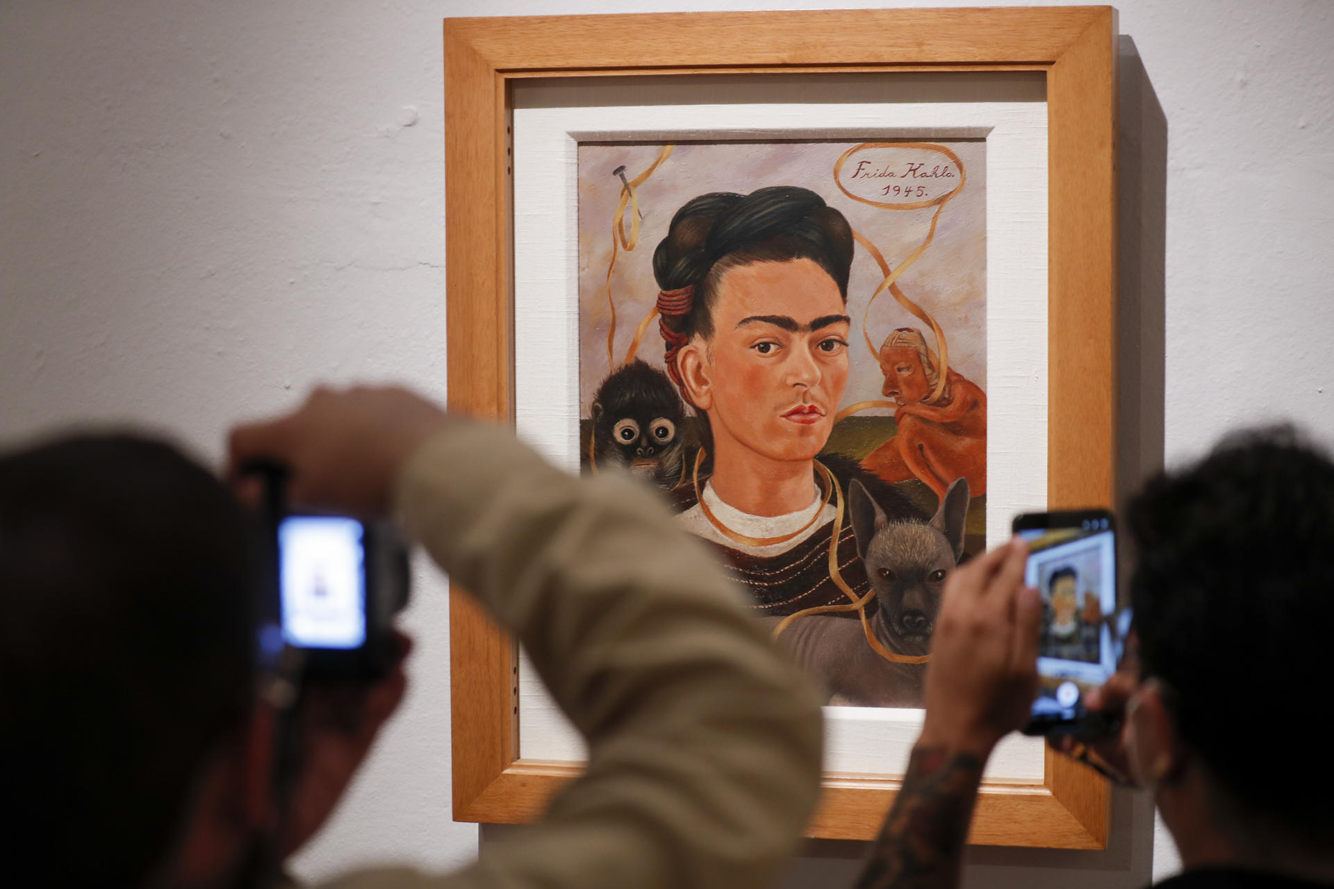 Personas toman fotografías de la obra 'Autorretrato con mono' de Frida Kahlo, durante un recorrido en el Museo Dolores Olmedo este viernes, en la Ciudad de México (México). EFE/Isaac Esquivel
