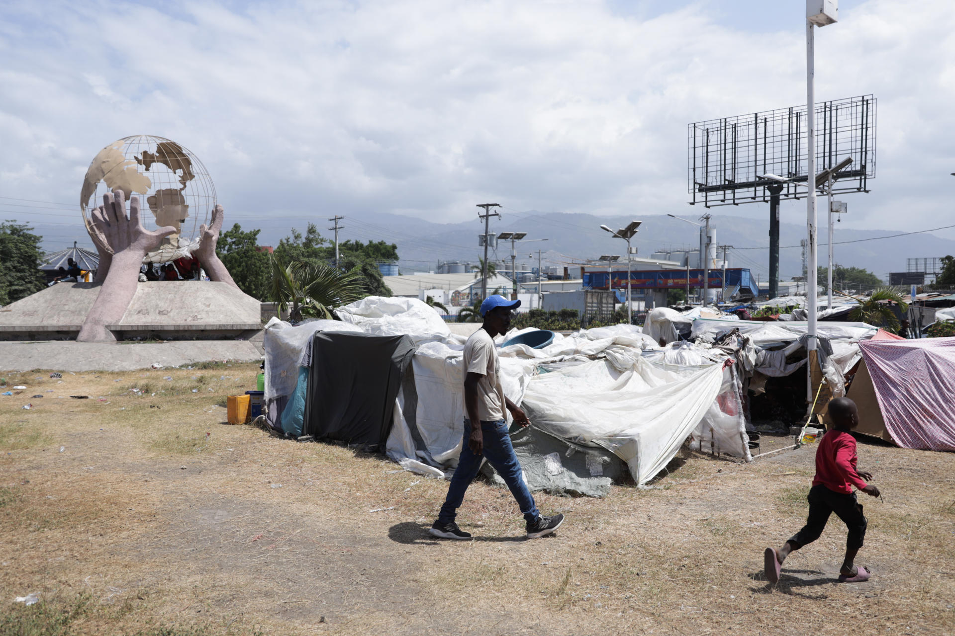Familias desplazadas por la violencia caminan en una zona de viviendas improvisadas, cerca al aeropuerto internacional Toussaint Louverture en Puerto Príncipe (Haití). EFE/ Patrice Noel
