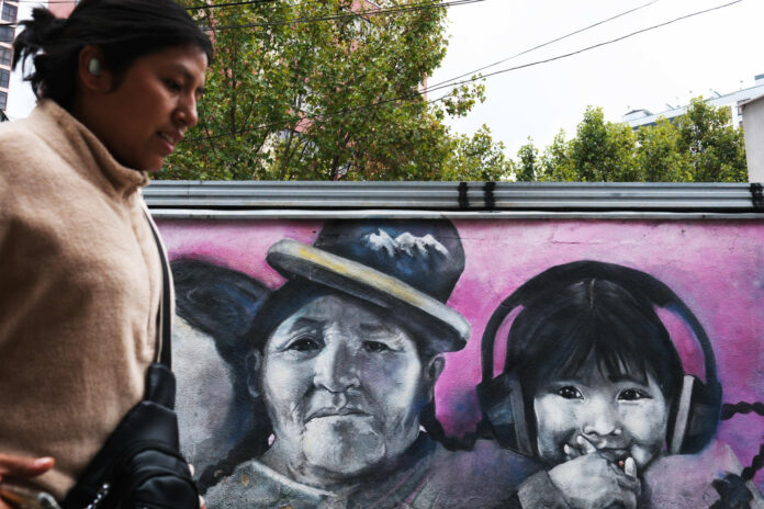 Fotografía de archivo que muestra a una persona caminando frente a un mural con el dibujo de una niña en La Paz (Bolivia). EFE/ Luis Gandarillas
