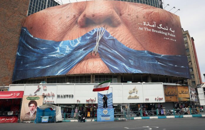 Un hombre sostiene la bandera nacional de Irán delante de una gran valla publicitaria antiestadounidense con un montaje del presidente de Estados Unidos Donald Trump y el estrecho de Ormuz, el pasado jueves 28 de mayo en la plaza Valiasr de Teherán, Irán. EFE/EPA/ABEDIN TAHERKENAREH RESTRICCIONES: SIN Acceso Medios Israel/Cadenas de Televisión en Idioma Persa Fuera de Irán/Estrictamente SIN Acceso BBC Persian/VOA Persian/Manoto TV/Iran International TV. (Según lo ordenado por la Dirección General de Medios Extranjeros de Irán) --
