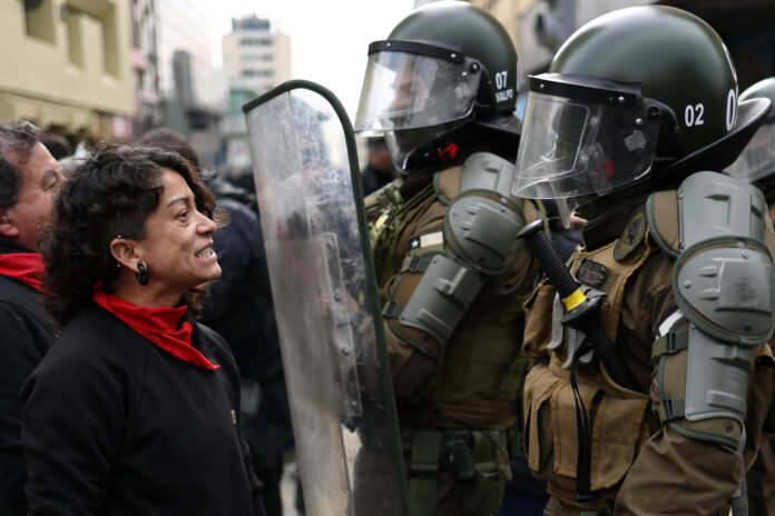 Una persona se enfrenta con la Policía de Chile en una manifestación a las afueras del Congreso Nacional durante el primer discurso de Presidente de Chile, José Antonio Kast, este lunes en Valparaíso (Chile). EFE /Javier Torres
