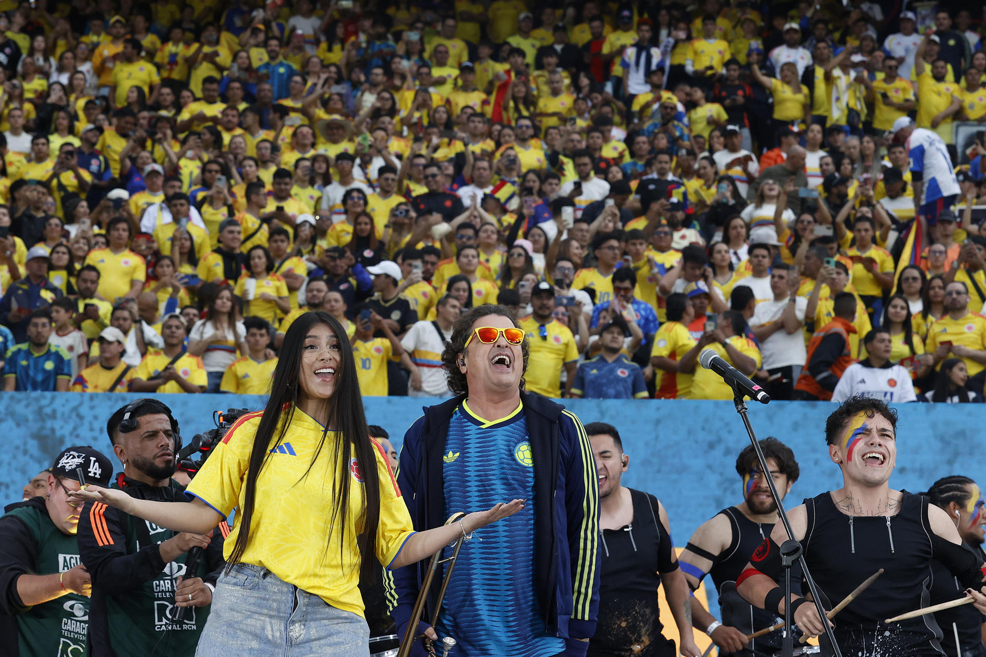 Los artistas colombianos Carlos Vives (c) y María Fuell (c-i) cantan este lunes antes del partido amistoso entre Colombia y Costa Rica previo a la Copa Mundial de Fútbol de 2026, en el estadio El Campín en Bogotá. EFE/ Mauricio Dueñas Castañeda

