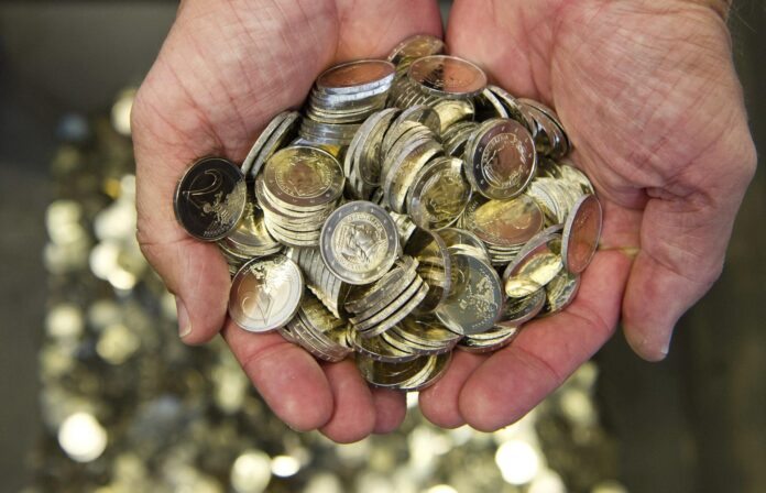 Un hombre sostiene en sus manos varias monedas de euro. EFE/Daniel Bockwoldt
