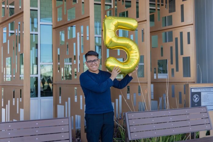 Fotografía divulgada por el Distrito de Escuelas Secundarias Phoenix Union donde aparece Joseph Parra Miguel, de 18 años e hijo de inmigrantes mexicanos, sosteniendo un globo en forma del número cinco en alusión a su logro de 5 millones de dólares en becas. EFE/ Distrito de Escuelas Secundarias Phoenix Union
