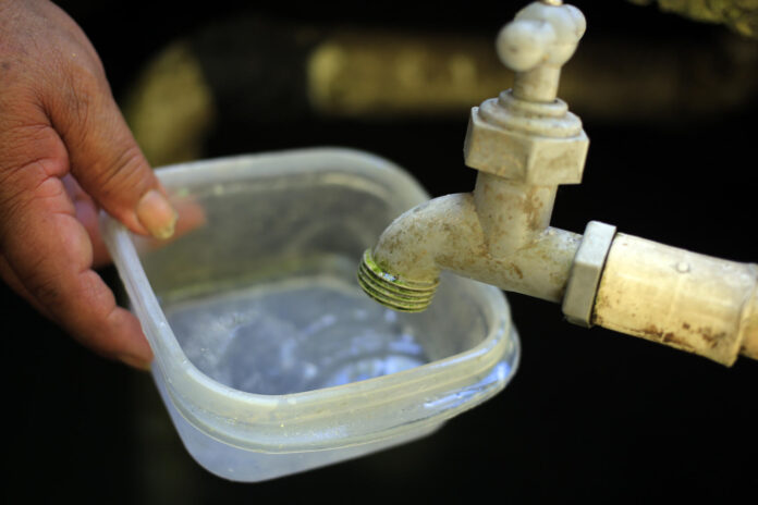 Fotografía de archivo de una persona intenta llenar un recipiente con agua. EFE/ Gustavo Amador

